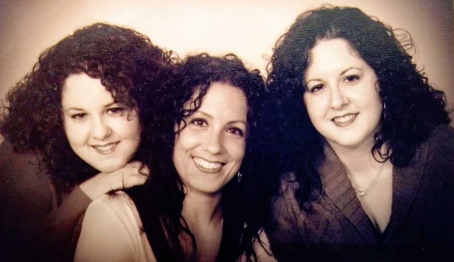 Twin sisters sit on either side of their older sister