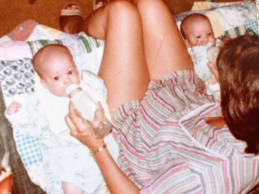 A woman feeds her twin babies using two bottles