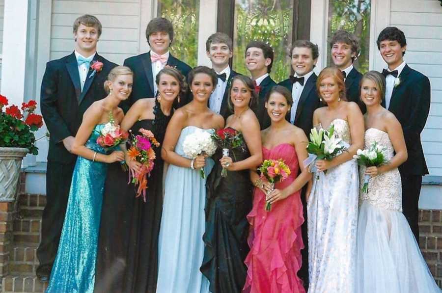 Prom picture of large group of boys and girls where the girls are holding bouquets 