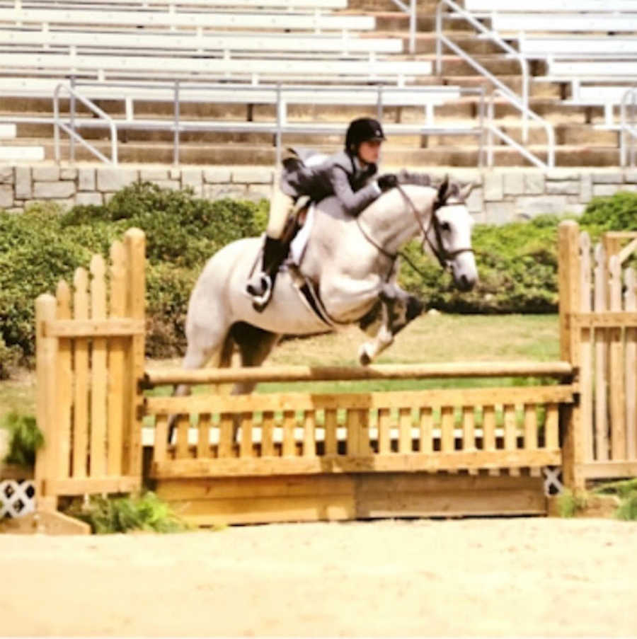 Equestrian doing jump with white horse