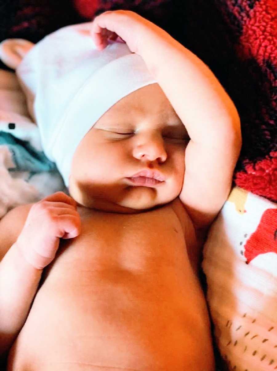 A baby boy wearing a white cap sleeping
