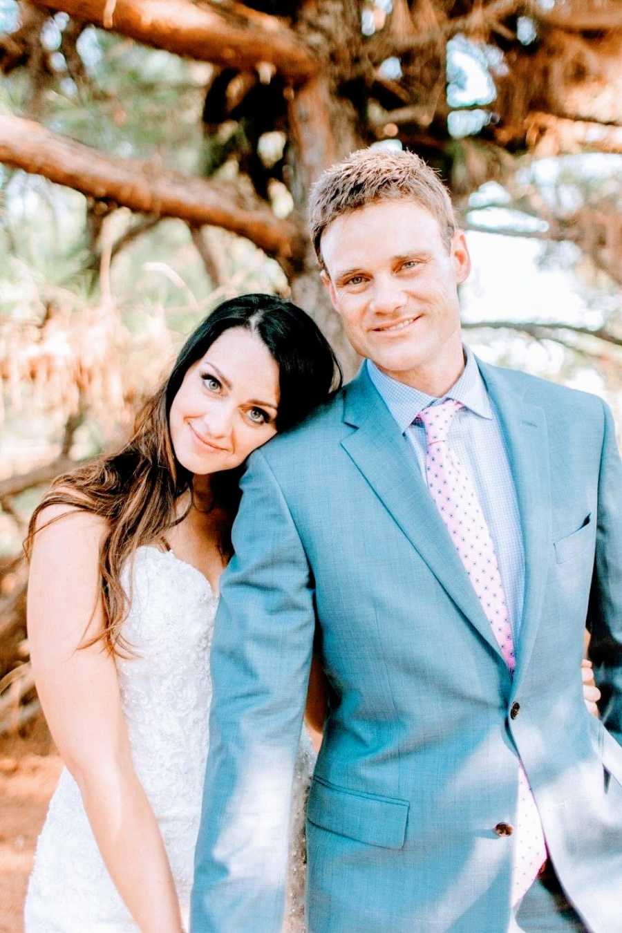 A bride leans on the shoulder of her groom outdoors