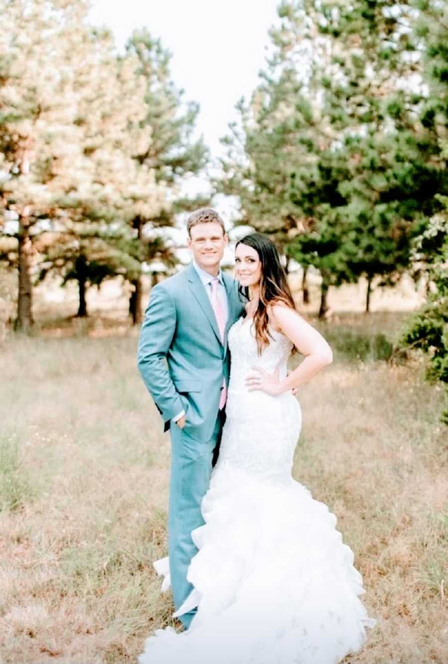 A bride and groom stand together in a field