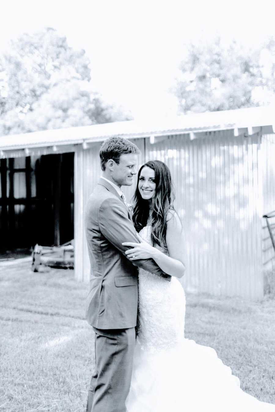 A bride and groom stand together outside a barn