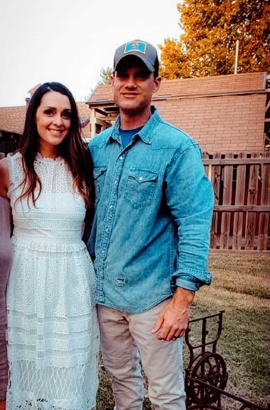 A young woman and her husband stand together outside