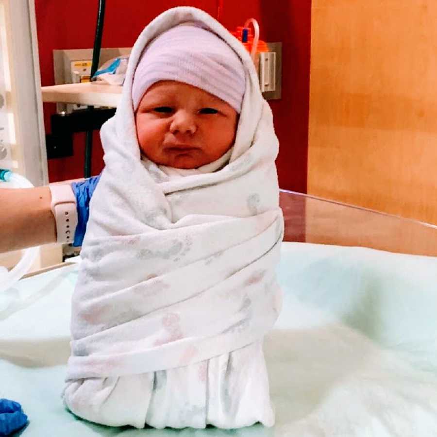 A baby boy swaddled in a white blanket in the hospital