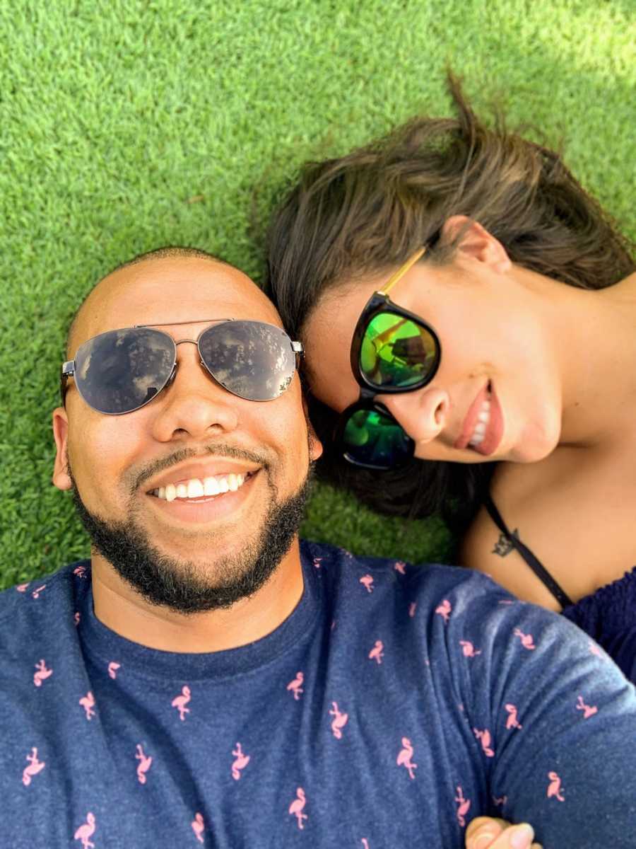 Couple lying on the grass wearing sunglasses taking selfie