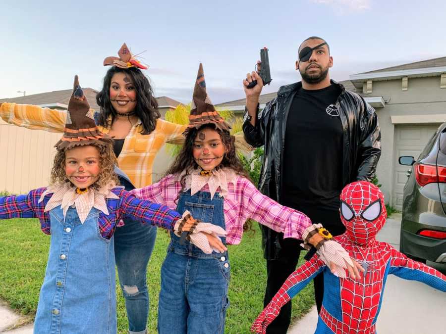 Family dressed in Halloween costumes posing outside