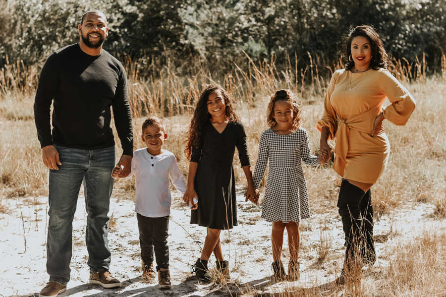 Family of five holding hands standing outside