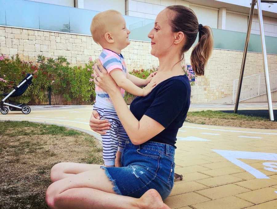Mom holding son outside and smiling