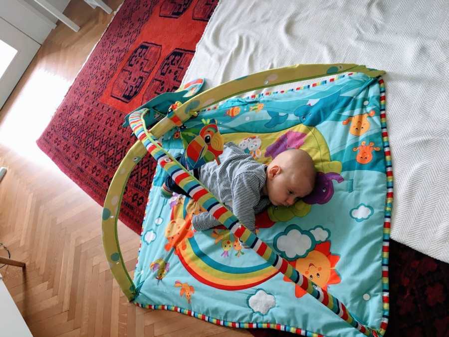 Newborn baby boy lying on playmat