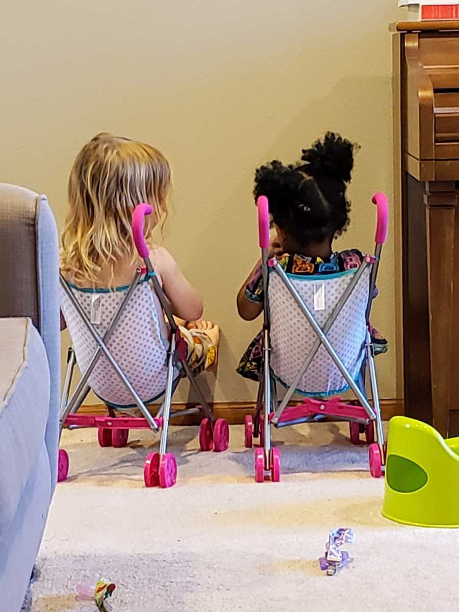 Foster sisters sitting in toy strollers talking