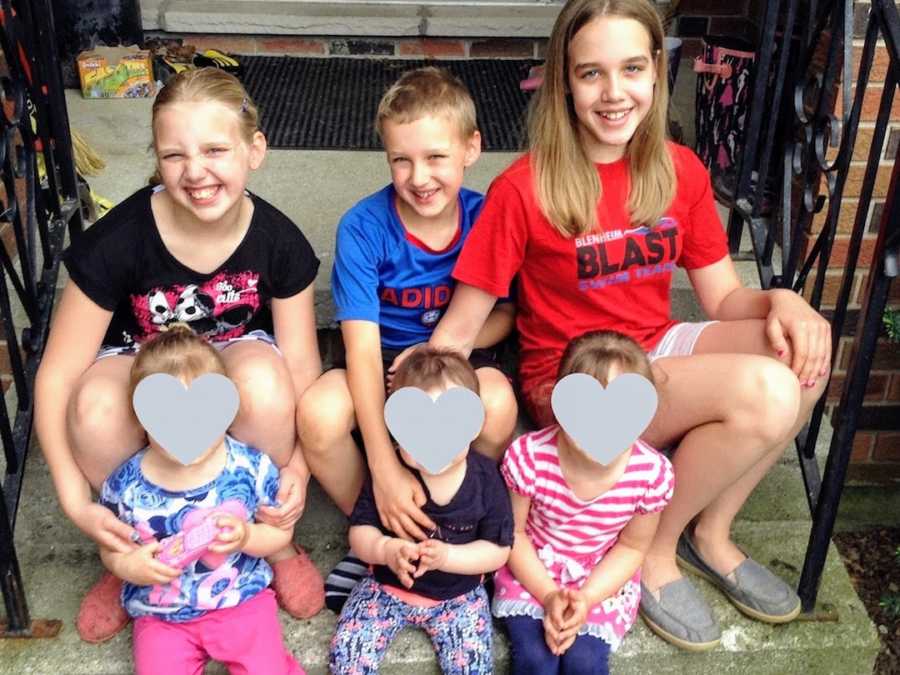 Six foster siblings sitting and smiling on front porch steps