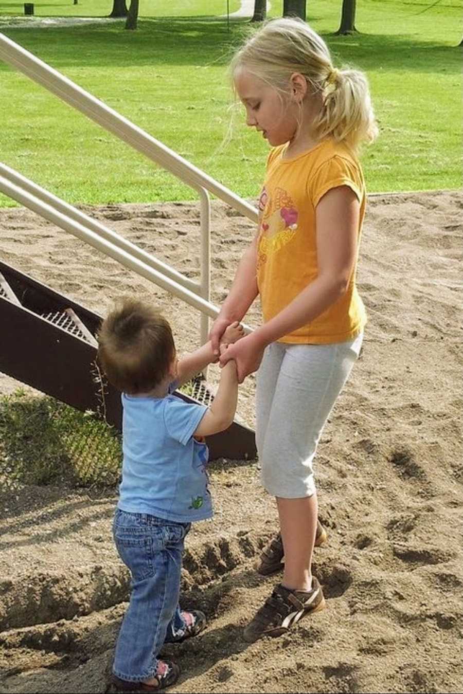 Foster siblings holding hands at playground