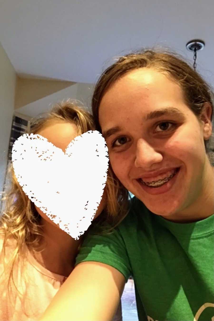 Young girl taking smiling selfie with foster sister