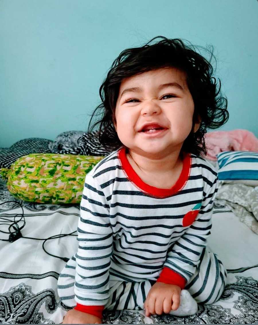 A hypersensitive little girl sitting on a bed in pajamas