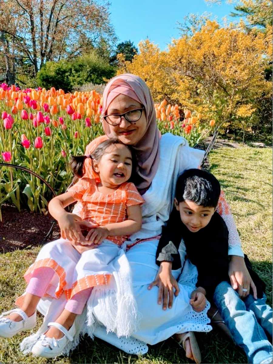 A neurodivergent mother holds her two children in her lap