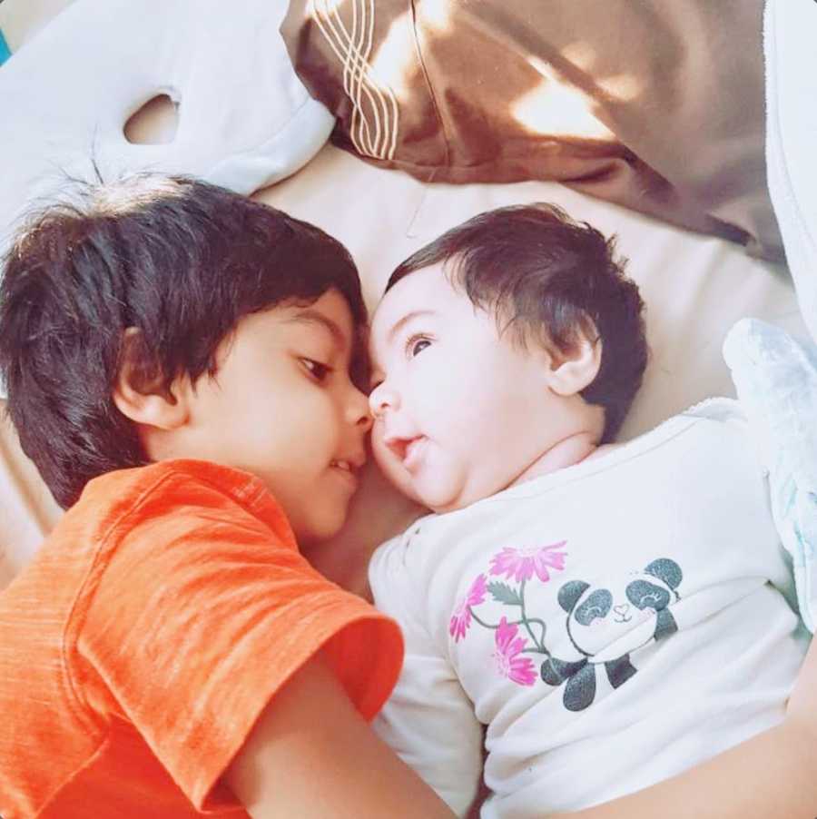 An autistic boy and his baby sister lie close together