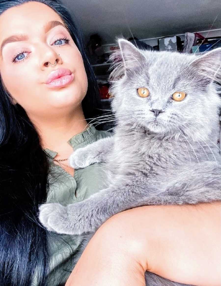 A woman with chronic illness holds a grey cat in her lap