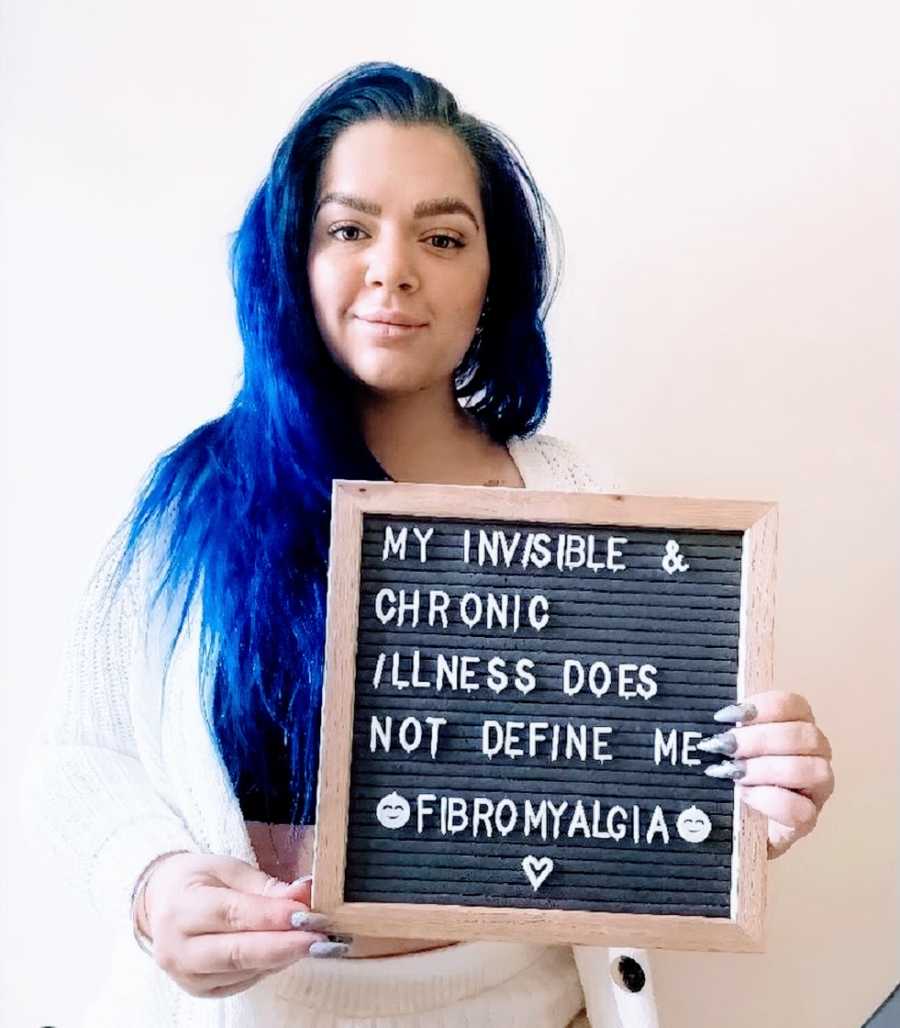 A woman holds a sign describing her chronic pain