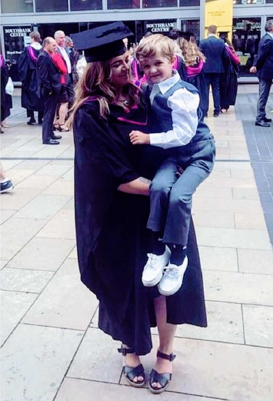 A woman with chronic illness holds her son at a graduation