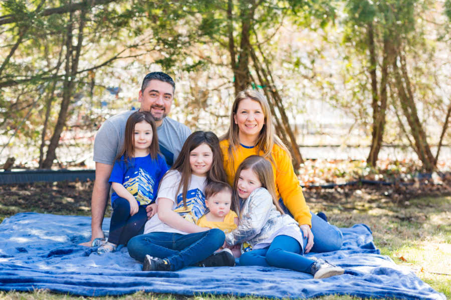 Family of 6 sitting on blue blanket outside