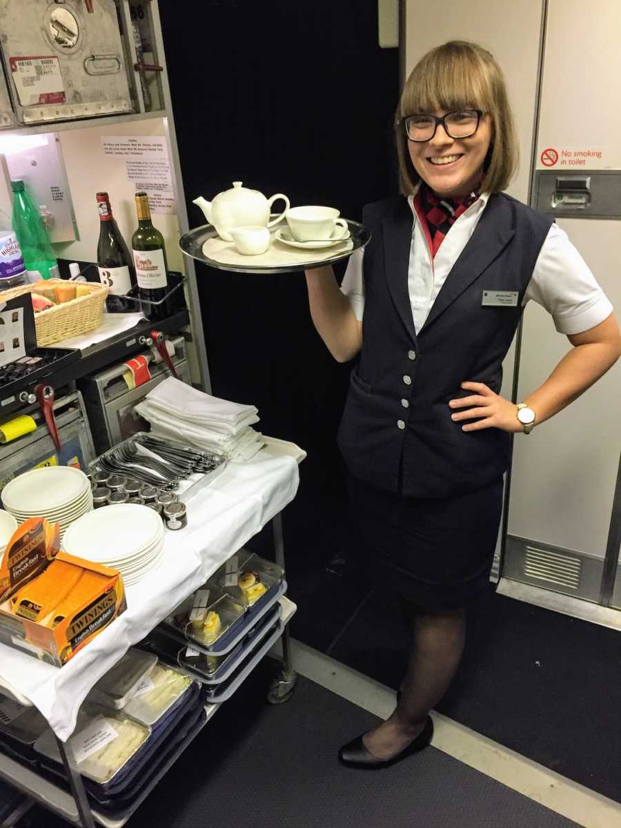 Flight attendant holding tea tray on airplane