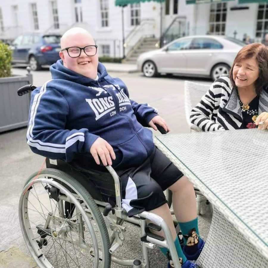 Man in wheelchair sitting at table with woman outside