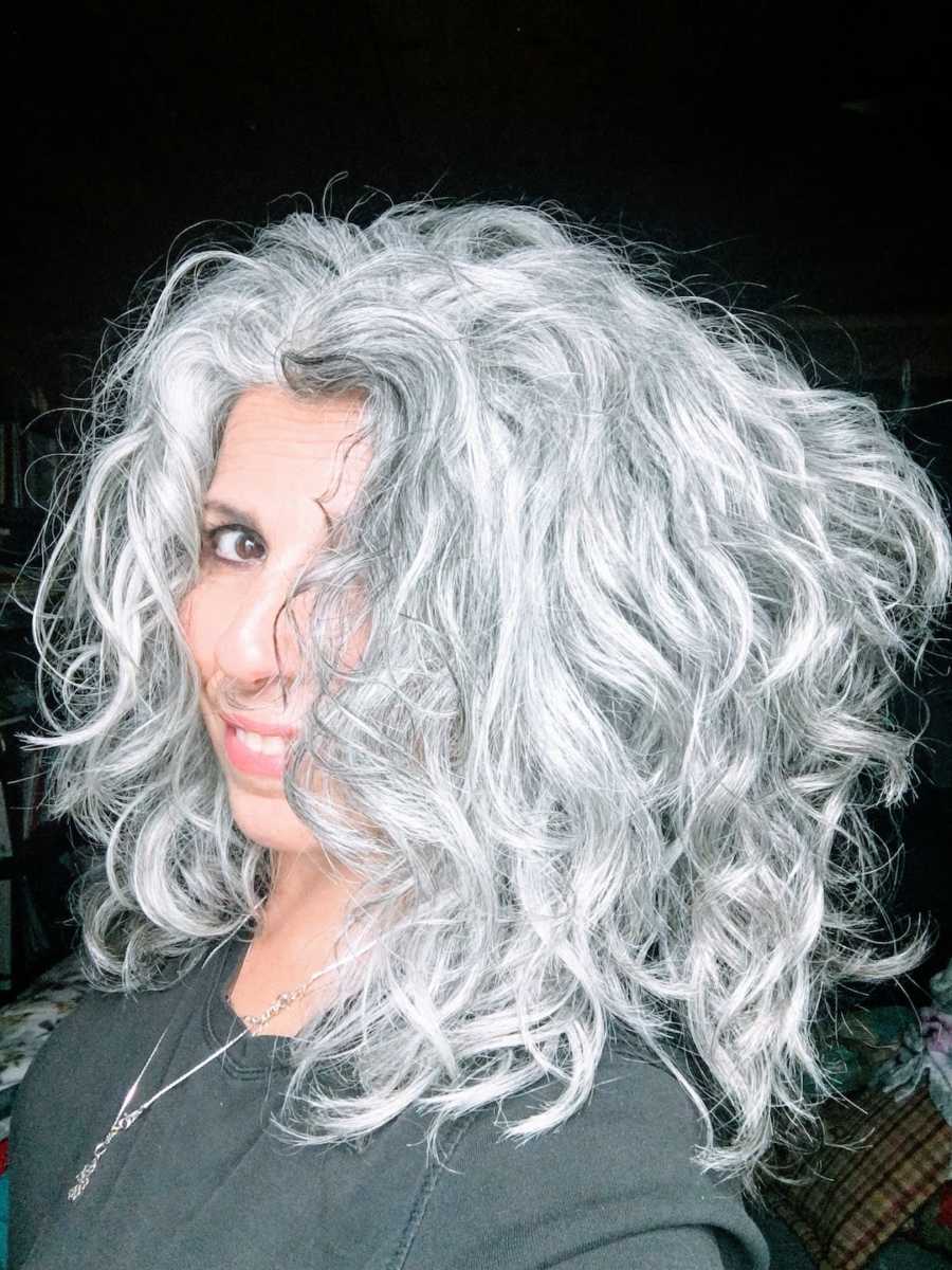 Woman with gray curly hair looking at camera taking a selfie