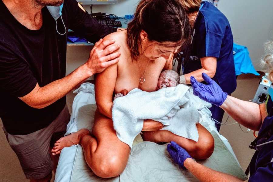 A mother holds her rainbow baby boy shortly after giving burth