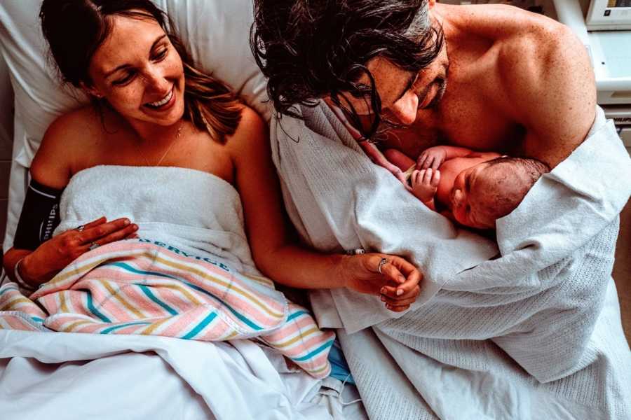 Parents hold their newborn rainbow baby in the hospital