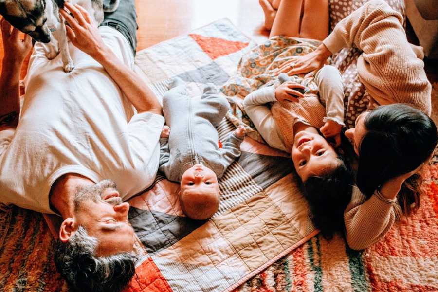 Parents and their two children lie together on a blanket