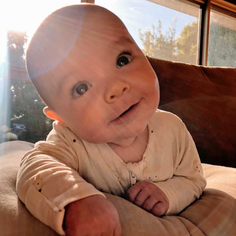 A baby boy with his head tilted sideways on a couch