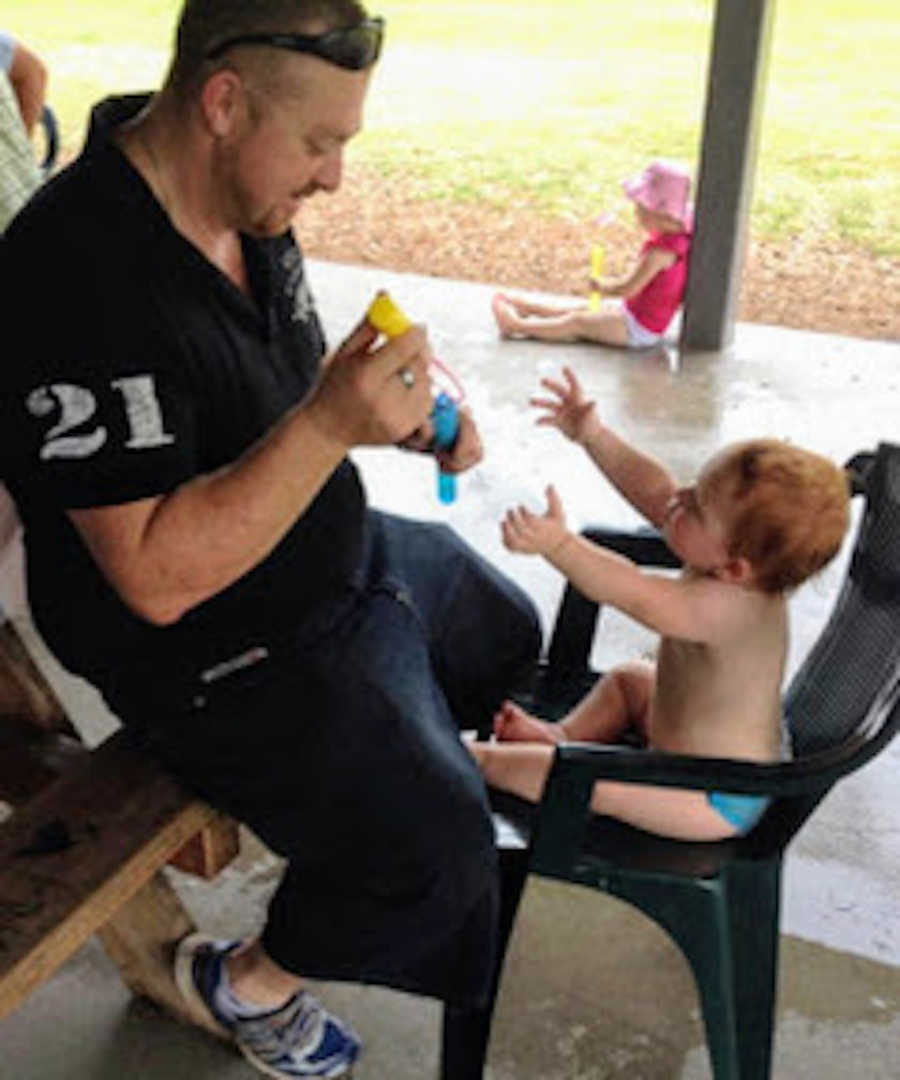 Dad sitting on bench with daughter reaching for him