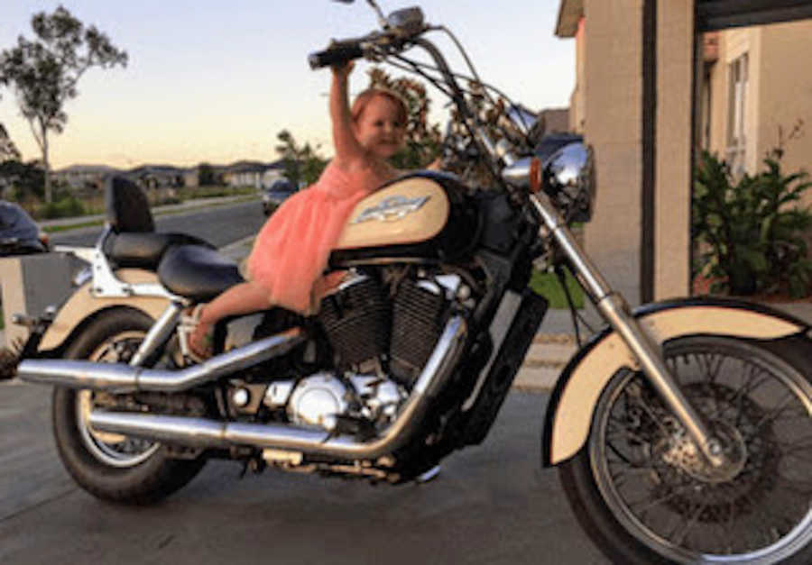 Young girl sitting on father's motorcycle