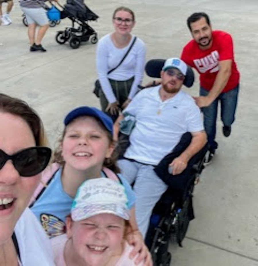 Family with father in wheelchair smiling outside