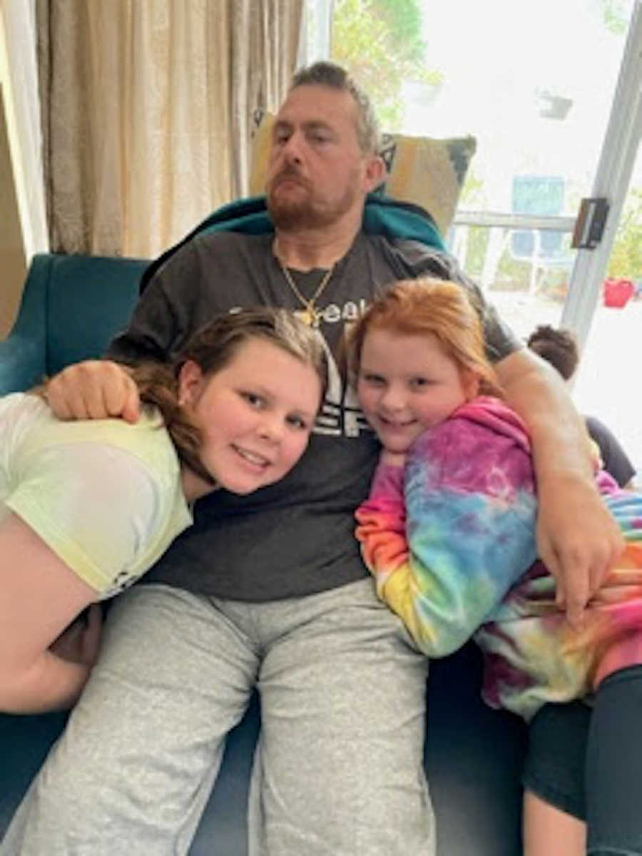 Father being hugged by his two daughters
