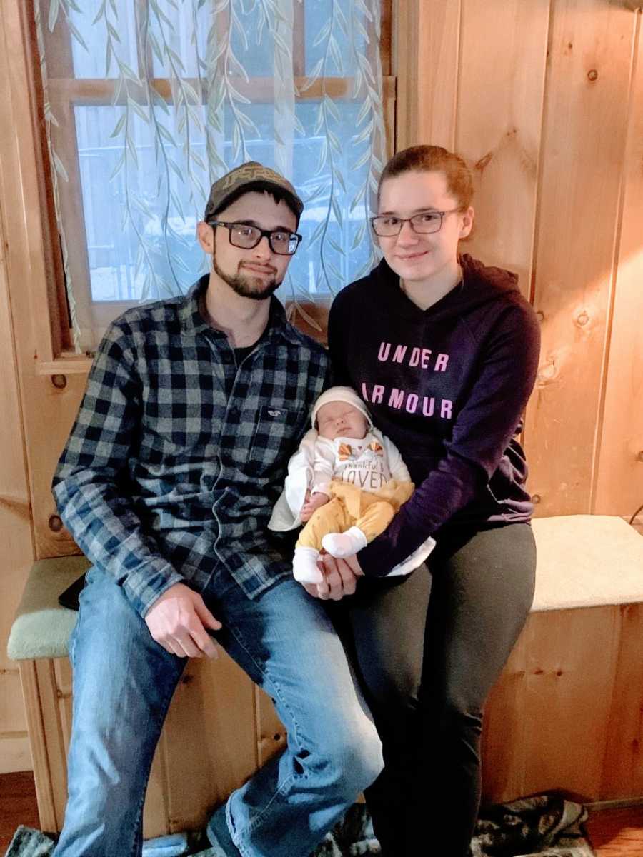First time parents take a family photo with their newborn daughter all bundled up for cold weather