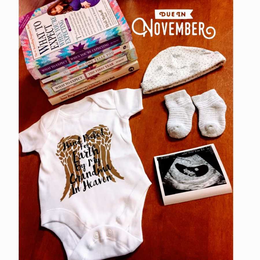 First time mom snaps photo of unborn baby's scan with onesie and pregnancy/motherhood books