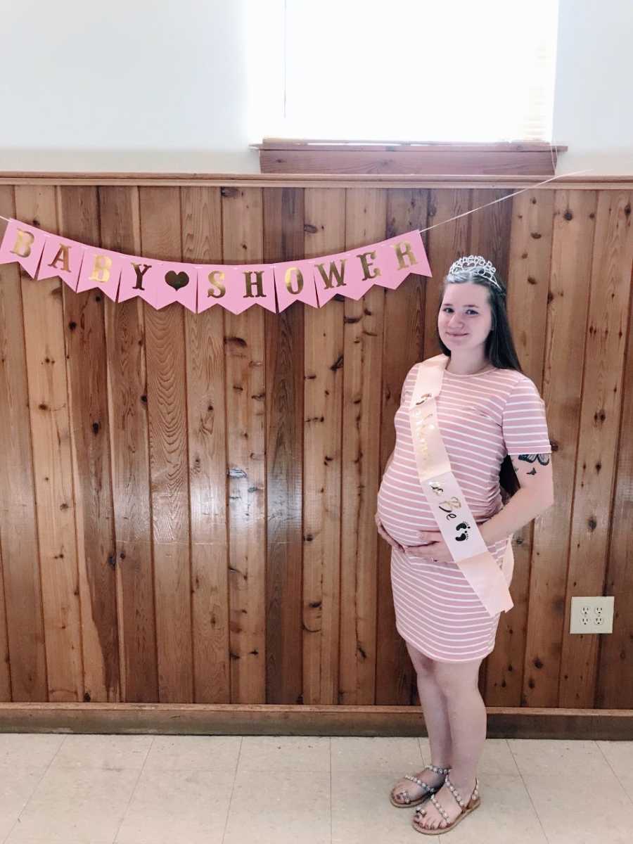 Woman expecting her first child holds her baby bump at her baby shower