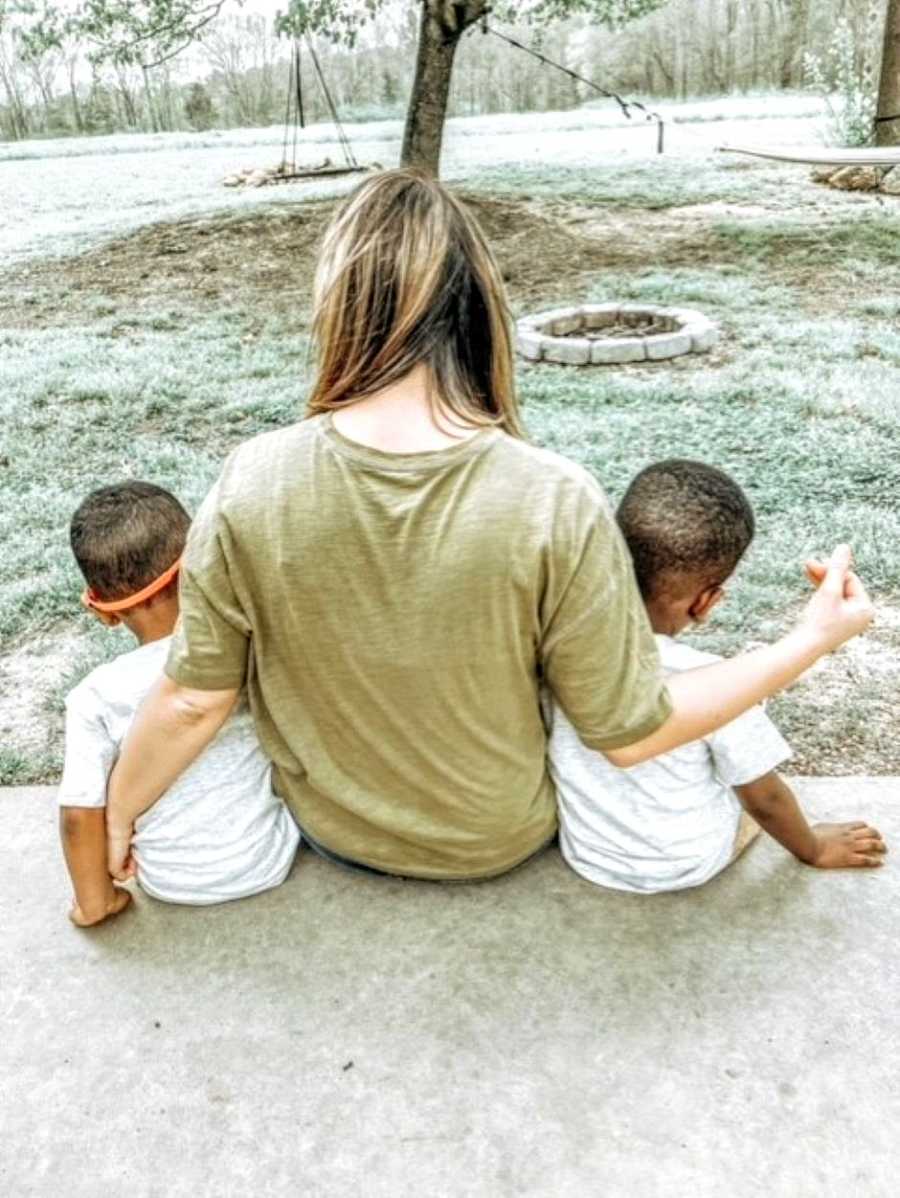 Mom takes photo with her two foster sons while sitting on the back porch, their backs facing the camera 