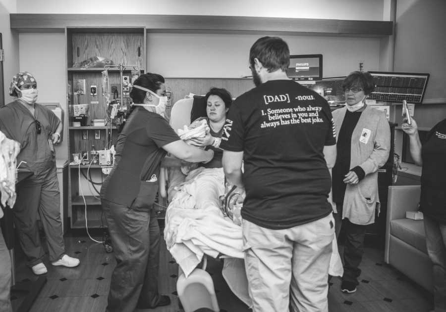 mom and newborn surrounded by dad and doctors