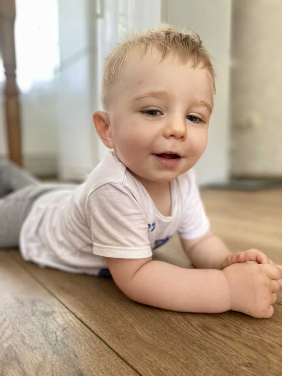 Little boy with spinal muscular atrophy crawls on the floor during playtime