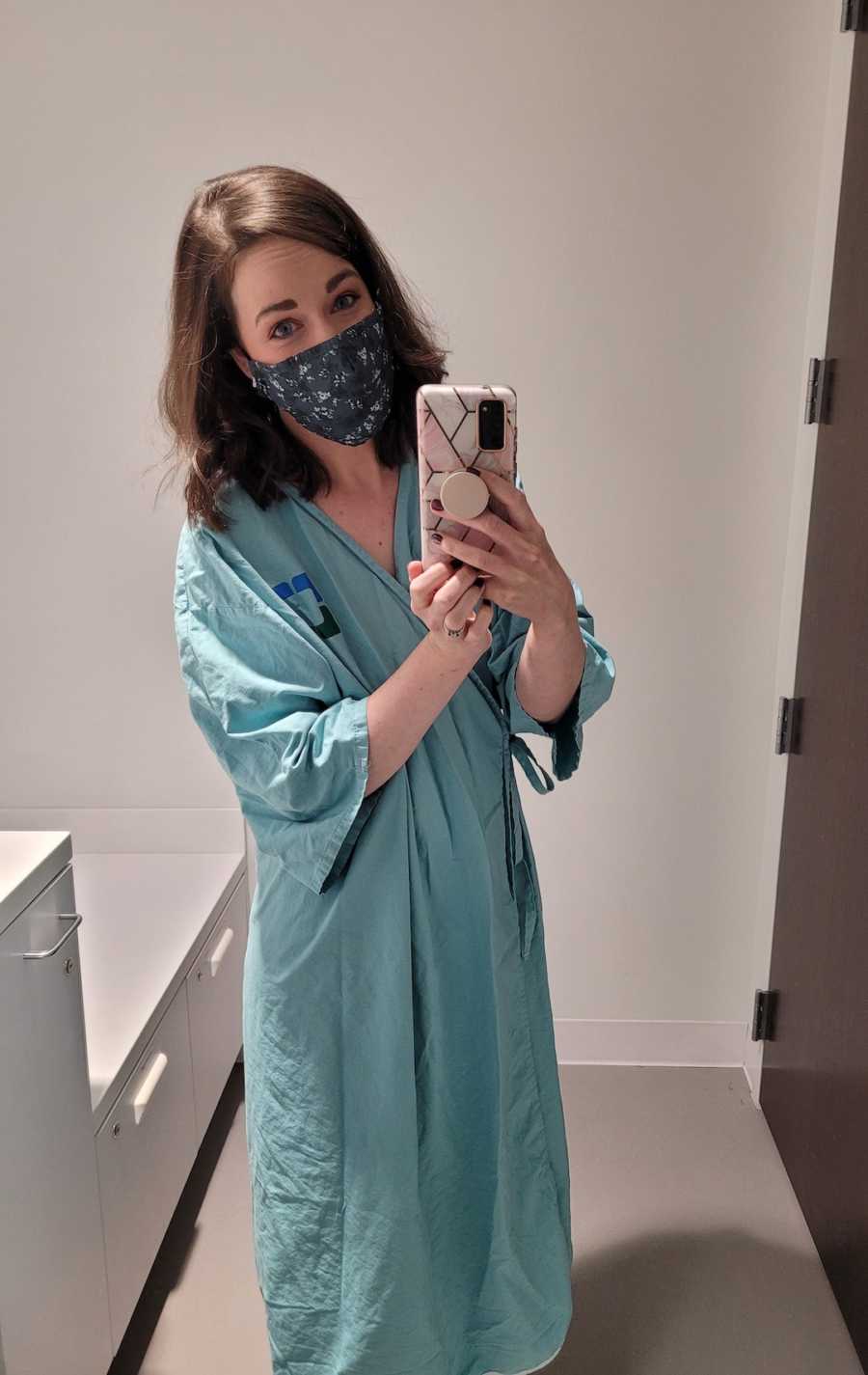 woman in hospital gown taking a mirror selfie