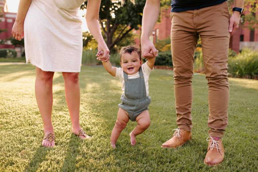 Couple take photo in their backyard as they try to help their adopted son walk
