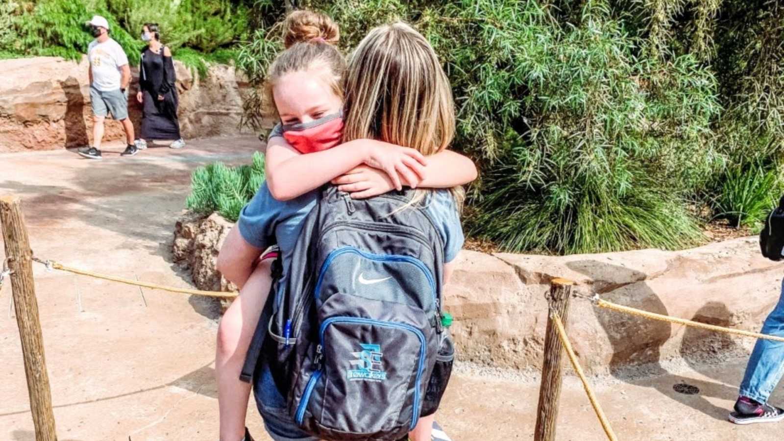 Girl mom proudly holds 9-year-old daughter during a trip at Disneyland