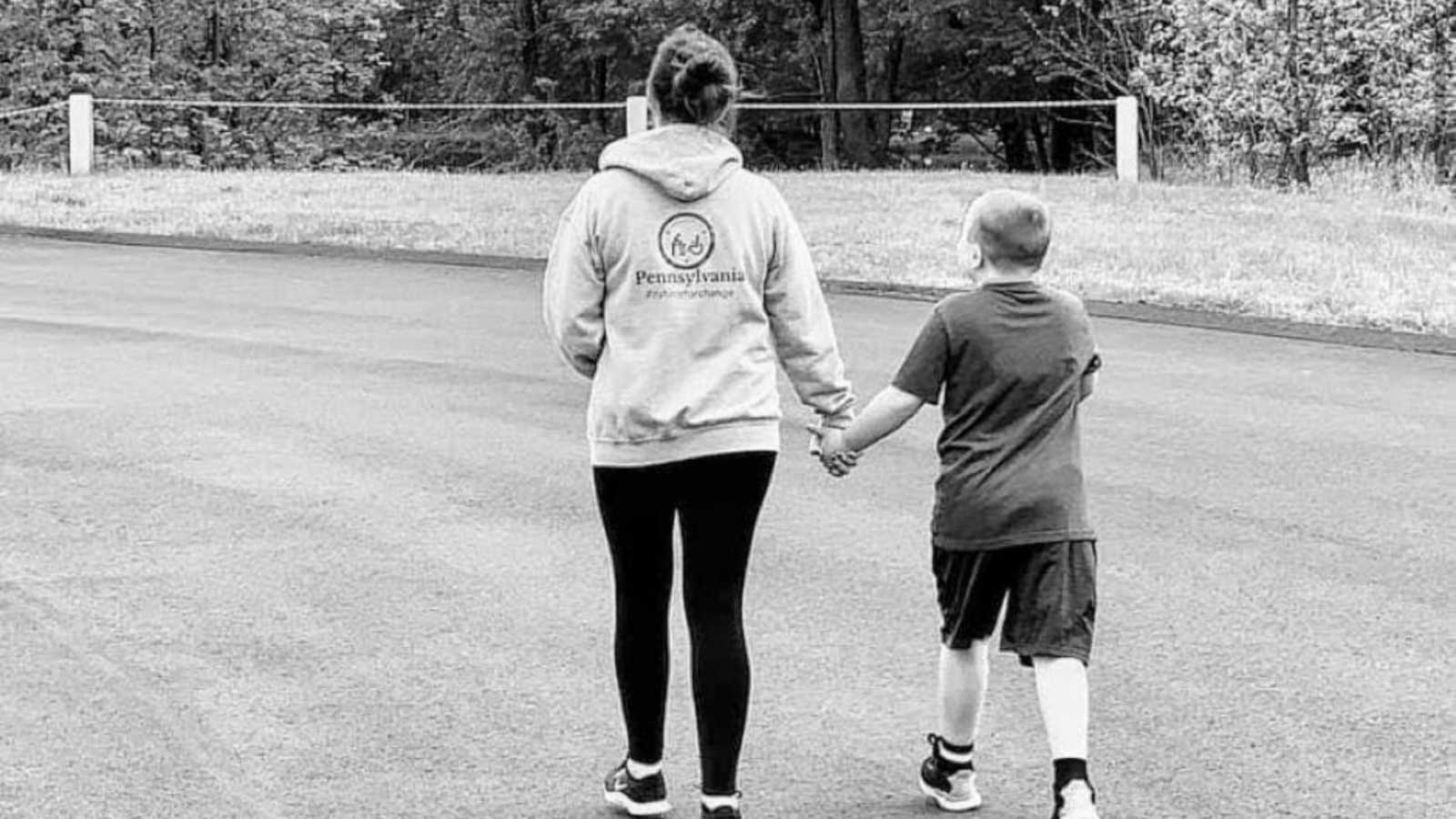 Mom proudly walks with autistic son down the street while holding hands