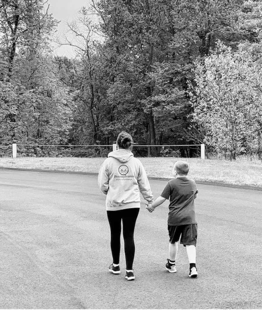 Special needs mom talks a walk with her autistic son while they hold hands