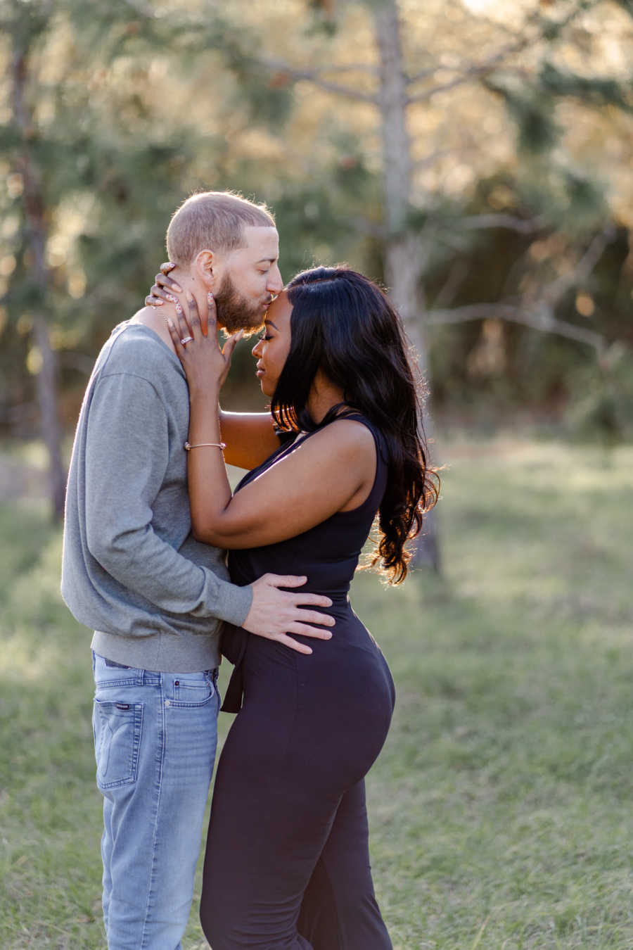 Young man kisses his wife on the forehead in intimate moment during a photoshoot