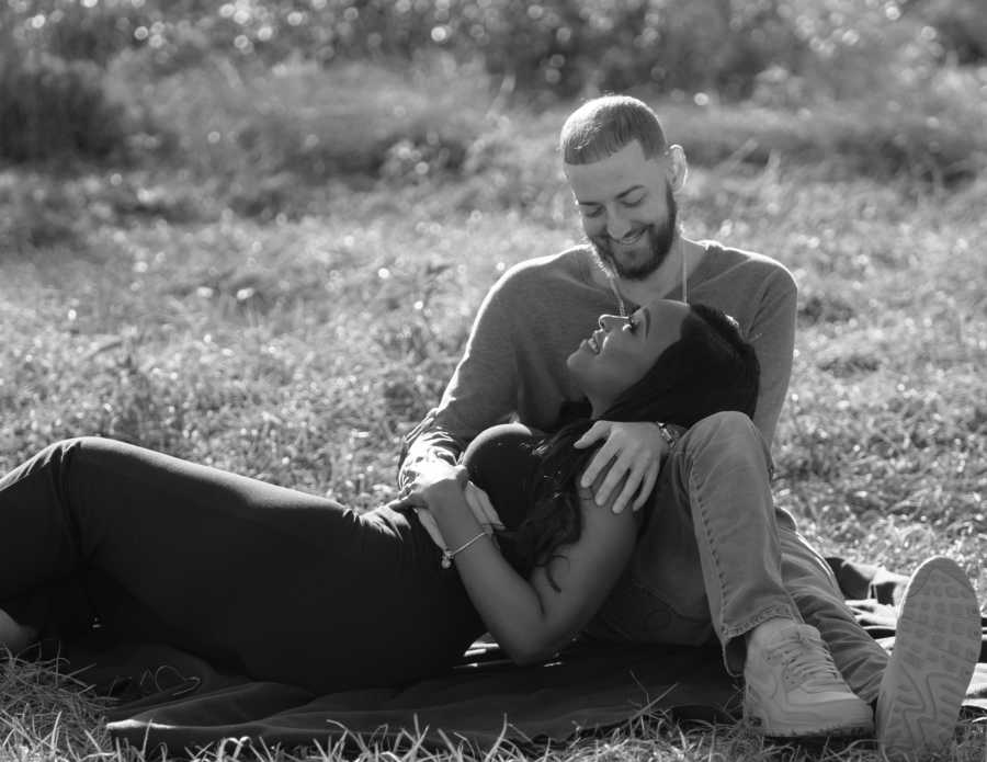 Young married couple lay together in a field during a photoshoot